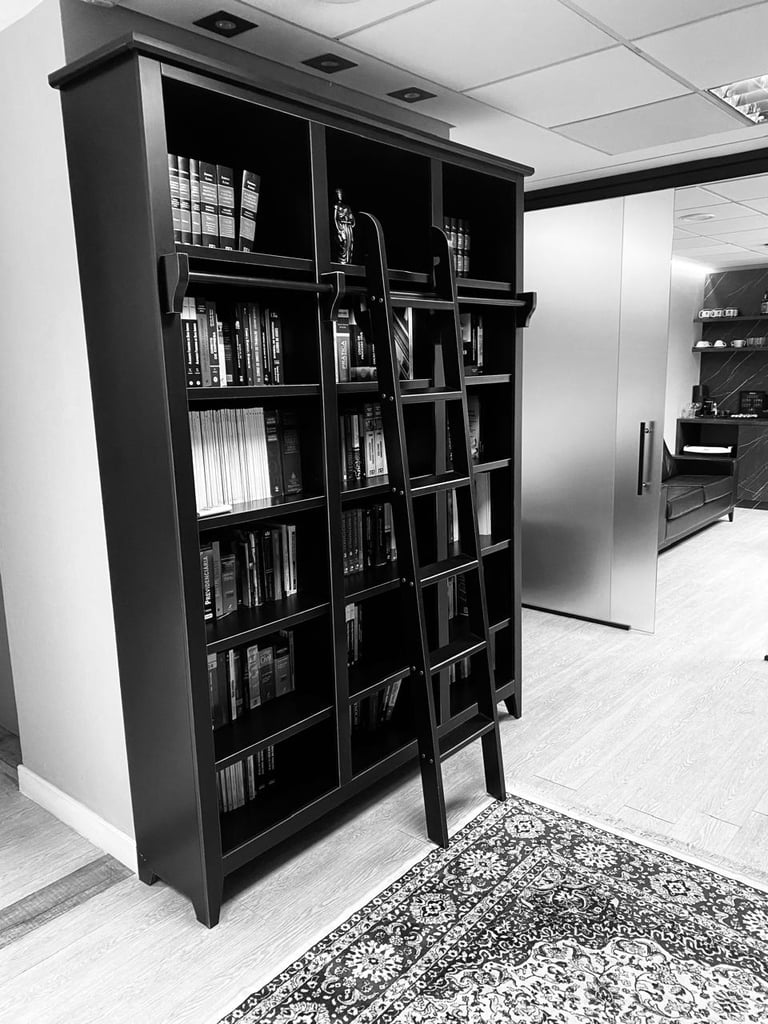 Black display cabinet with glass doors filled with DVDs and media in a modern interior space, black and white photograph